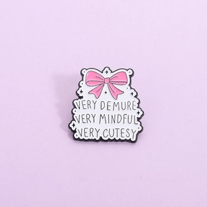 Pink bow enamel brooch featuring Very Demure Very Mindful slogan on a white badge base