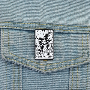 Tarot style enamel brooch with a witch and black cat on a blue denim jacket pocket