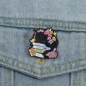 Broche en émail chat noir sur livres avec fleurs colorées sur veste en jean