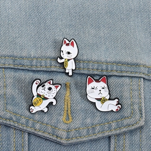 Lot de trois pin's émaillés chat porte-bonheur sur fond de veste en jean bleue