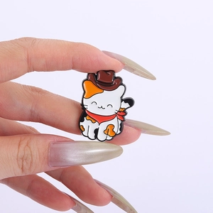 Dettaglio della spilla in smalto a forma di gatto calico con cappello e sciarpa