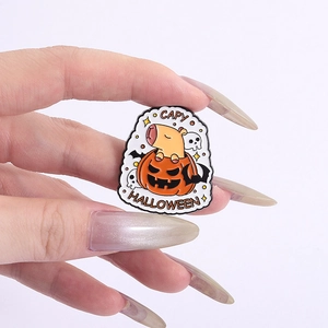 Detail of Capybara Halloween enamel pin with pumpkin and bats shown in hand