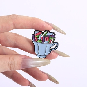 Détail d'un pin's en émail tasse de thé bleue remplie de livres colorés pour veste