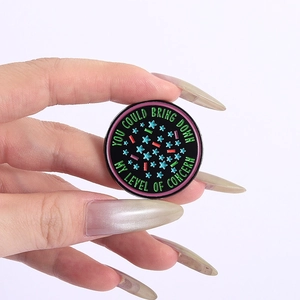 Detailed close-up of a round enamel pin featuring green text on a black background
