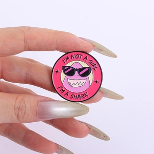 Makroaufnahme einer rosa Hai-Emaille-Anstecknadel mit dem Text I'M NOT A GIRL I'M A SHARK