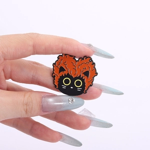 Gros plan sur la broche chat en émail noir avec cheveux bouclés oranges et yeux jaunes
