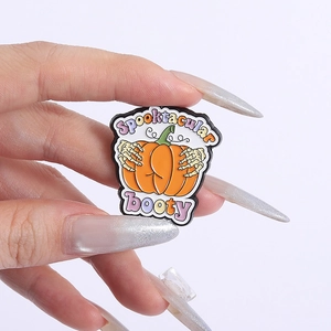 Detail of creative pumpkin booty enamel pin with skeleton hands and Spooktacular booty text