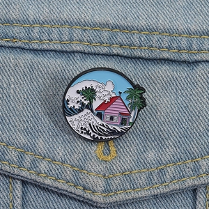 Anime-inspired enamel pin featuring a pink cottage and ocean waves on denim fabric