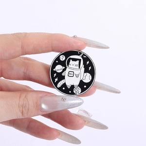 Detailed close-up of a round astronaut cat enamel pin held by hand with space elements