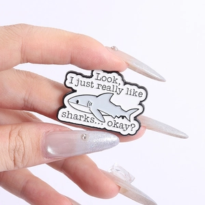 Detail of shark enamel pin with 'Look, I just really like sharks... okay?' text