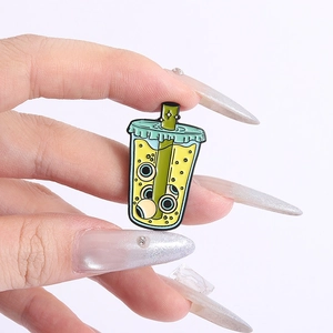 Close-up of funny milk tea enamel pin featuring unique eyeball designs and green straw
