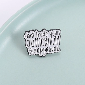Broche en émail avec message inspirant posée sur un plat en céramique couleur menthe douce