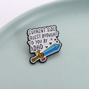 Sword enamel pin badge with ADHD Current Side Quest text on a ceramic plate