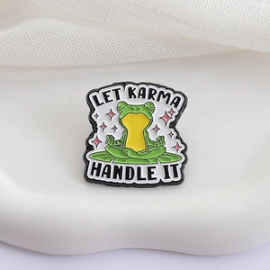 Spilla in smalto a forma di rana yoga in meditazione con testo Let Karma Handle It