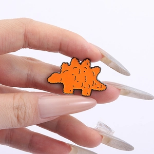 Macro d'une broche en émail en forme de nugget de poulet dinosaure orange avec texture