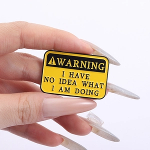 Detail of enamel warning sign brooch featuring 'I HAVE NO IDEA WHAT I AM DOING' text