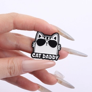 Detail of white cartoon cat enamel pin with sunglasses and Cat Daddy text