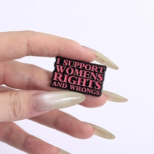 Detail of hand holding a black enamel pin with I Support Womens Rights and Wrongs text