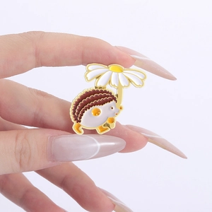 Close-up of a cute hedgehog holding a white daisy umbrella enamel pin held by hand