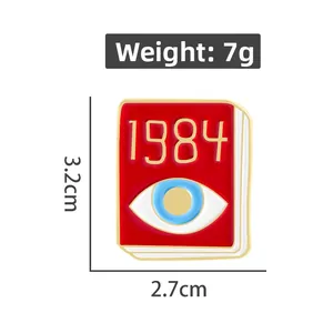 Detailed view of red 1984 book enamel pin with blue eye, measuring 3.2cm by 2.7cm