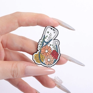 Detail of medical stethoscope enamel brooch with colorful flowers held by a hand