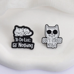 Set of two cute black and white enamel cat brooches with funny quotes on a white stand