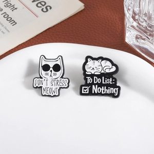Cute black and white cat enamel pins with funny slogans in a stylish ceramic dish