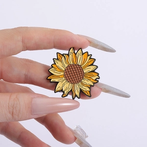 Gros plan d'un pin's émaillé en forme de tournesol avec des détails métalliques jaunes