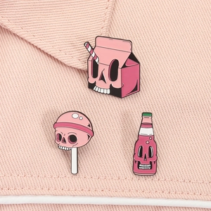 Vue détaillée de trois épingles en émail rose à motif de crâne sur tissu denim rose clair