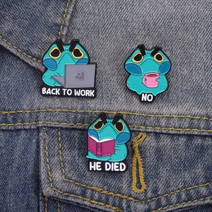 Close-up of three grumpy frog enamel pins styled on a blue denim jacket pocket