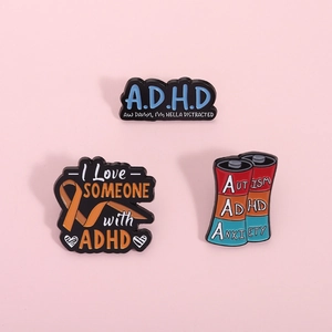 Three enamel pins for ADHD awareness featuring colorful battery and ribbon designs