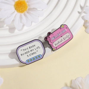 Close-up of enamel pins set featuring Bookish Girlie and 5 stars book review designs