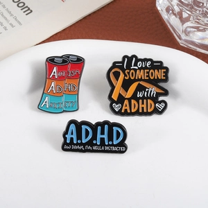 Detailed close-up of ADHD and Autism enamel pins on a white plate with aesthetic background