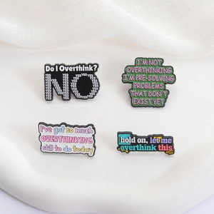 Lot de quatre pin's en émail coloré avec citations humoristiques sur fond blanc épuré