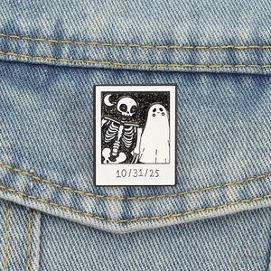 Broche en émail d'Halloween avec squelette et fantôme sur une veste en jean bleue