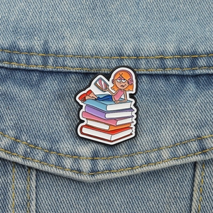 Cartoon enamel pin of girl with headphones on books pinned to a denim jacket