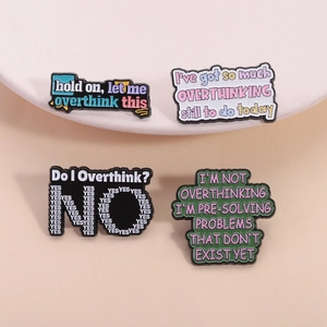 Détail de quatre épingles en émail colorées avec des citations créatives sur l'overthinking