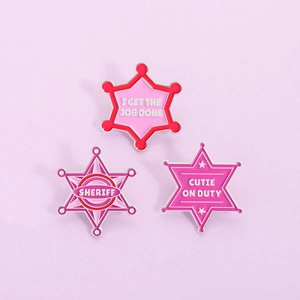 Set aus rosa Emaille-Anstecknadeln in Sternform mit Sheriff-Motiv und englischen Texten