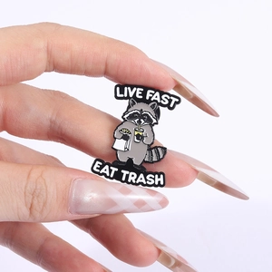 Detailed close-up of an enamel pin featuring a cute raccoon with Live Fast Eat Trash text