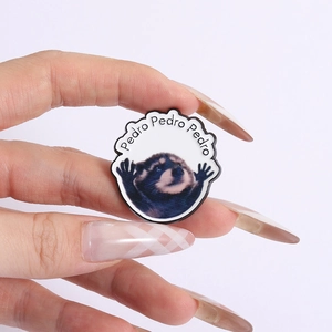 Detail of Pedro Raccoon enamel pin held by fingers to show size and metal texture