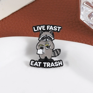 Cute raccoon enamel pin with 'Live Fast Eat Trash' text and soda fries on ceramic