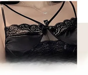 Detail of black silk camisole featuring delicate lace trim and cross-strap neckline