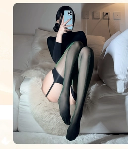 Détail de bas noirs transparents avec paillettes vertes et porte-jarretelles intégré chic