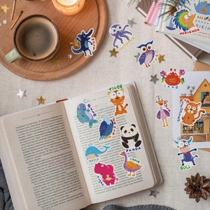 Close-up of 15 waterproof cartoon animal stickers with English names on a desk