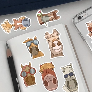 Close-up of funny cartoon horse stickers with creative sunglasses on a notebook
