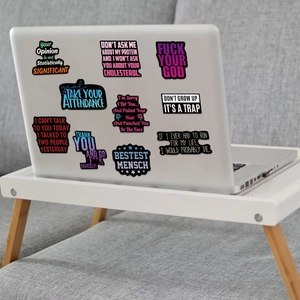 Close-up of waterproof black graffiti stickers with sarcastic quotes on a laptop