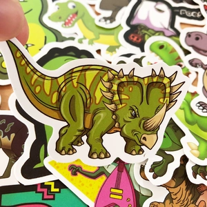 Close-up of a green cartoon triceratops sticker held by hand from a 50pcs dinosaur set