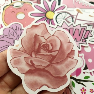 Close-up of pink cute stickers featuring rose, donut, and owl designs for suitcases