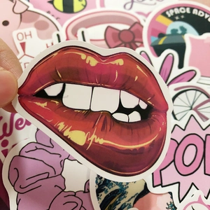Detail of pink cartoon graffiti stickers being applied to a laptop and luggage case