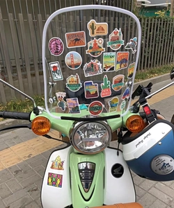 Waterproof world travel landmark stickers applied to a green motorcycle windshield